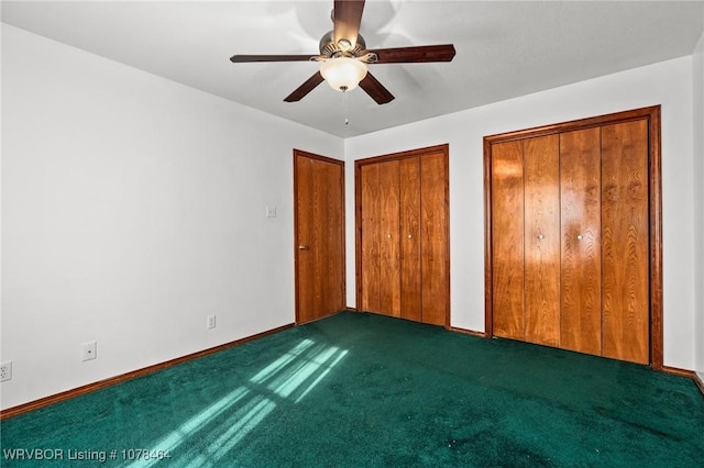 unfurnished bedroom featuring ceiling fan, two closets, and dark carpet