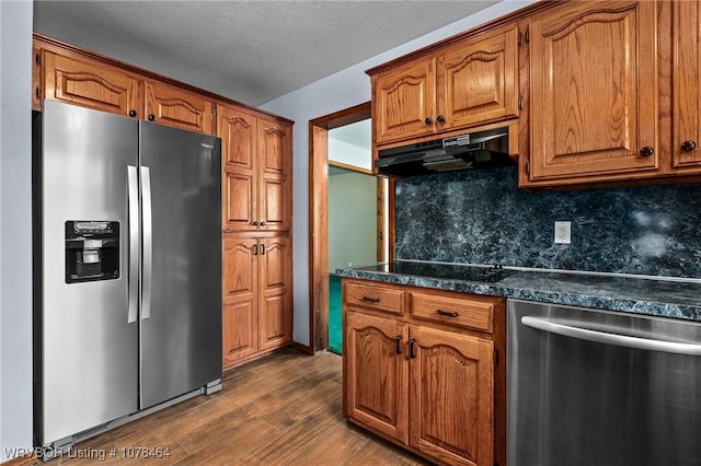 kitchen featuring a textured ceiling, dark hardwood / wood-style floors, stainless steel appliances, and backsplash