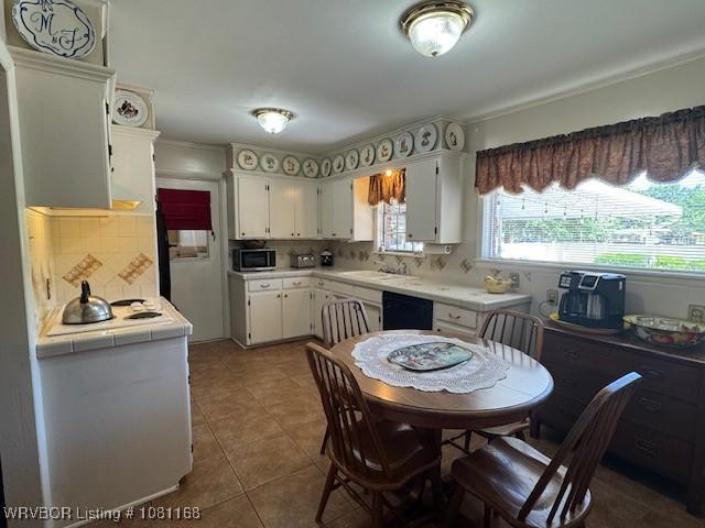 216 Jefferson Dr, Charleston, AR 72933 - kitchen with stainless steel microwave, white cabinetry, backsplash, and crown molding