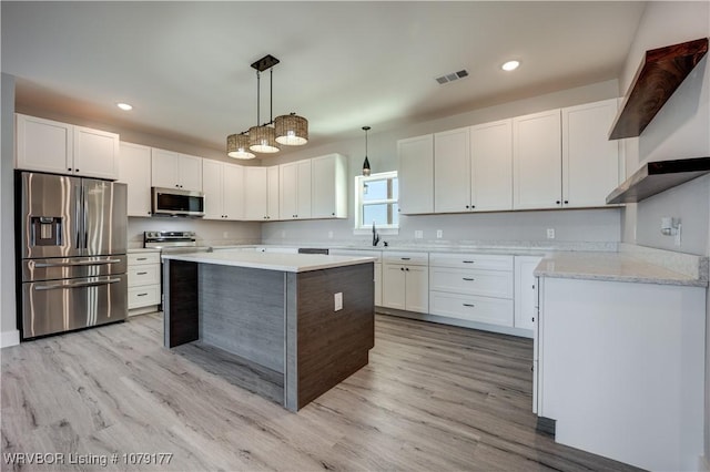 kitchen featuring pendant lighting, stainless steel appliances, a kitchen island, and white cabinets