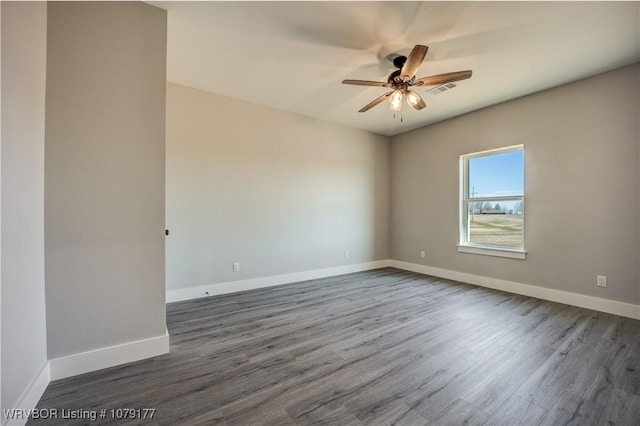 unfurnished room featuring dark wood-style floors, baseboards, visible vents, and ceiling fan