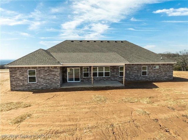 back of house with a patio area, a shingled roof, and brick siding