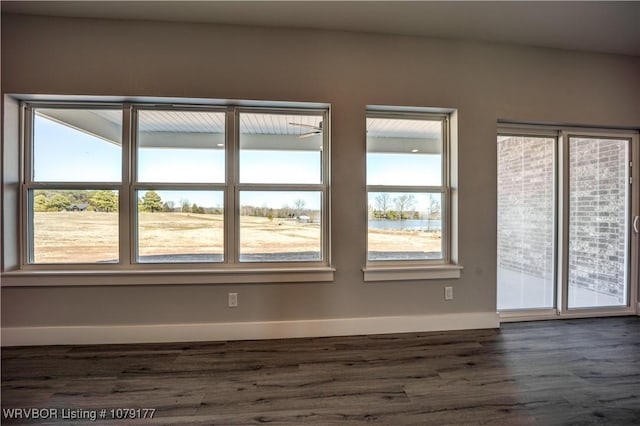 empty room featuring dark wood-type flooring and baseboards