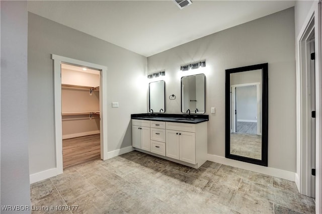 full bath with double vanity, a sink, visible vents, and baseboards