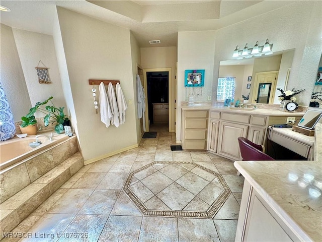 bathroom featuring tile patterned flooring, vanity, and tiled bath