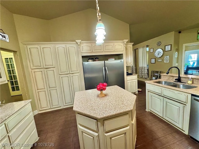 kitchen with cream cabinetry, sink, stainless steel appliances, and hanging light fixtures