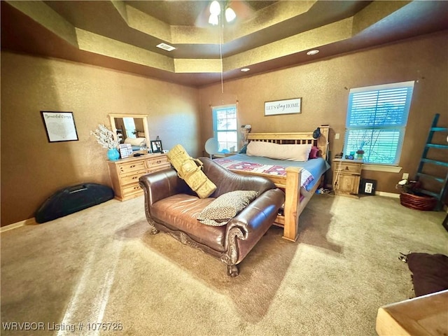 bedroom featuring carpet flooring, a tray ceiling, and ceiling fan