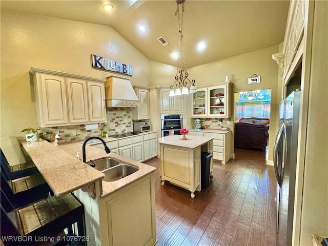 kitchen featuring premium range hood, a breakfast bar, sink, a kitchen island, and hanging light fixtures