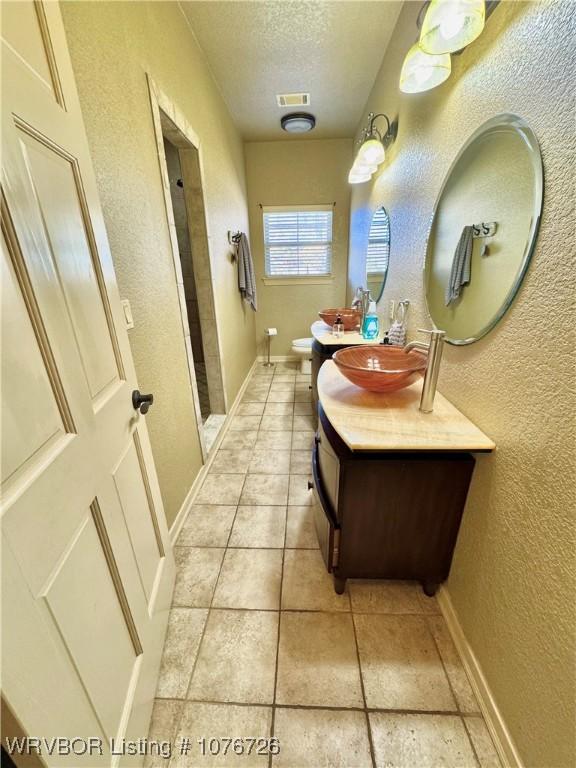 bathroom featuring a shower, vanity, a textured ceiling, and toilet