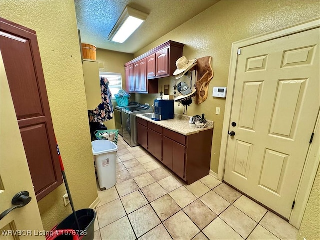 kitchen featuring washing machine and clothes dryer, light tile patterned floors, and a textured ceiling