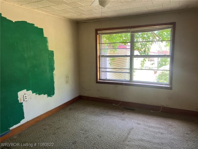 carpeted spare room with baseboards, a healthy amount of sunlight, and visible vents