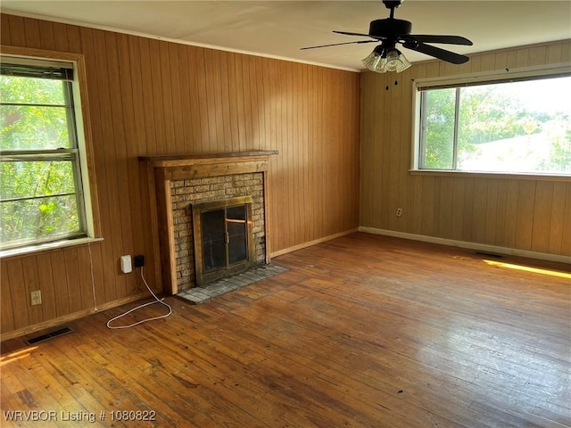 unfurnished living room featuring visible vents, a fireplace, a healthy amount of sunlight, and hardwood / wood-style flooring