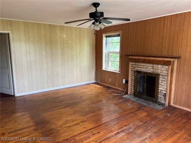 unfurnished living room with hardwood / wood-style flooring, a fireplace, ceiling fan, wooden walls, and baseboards