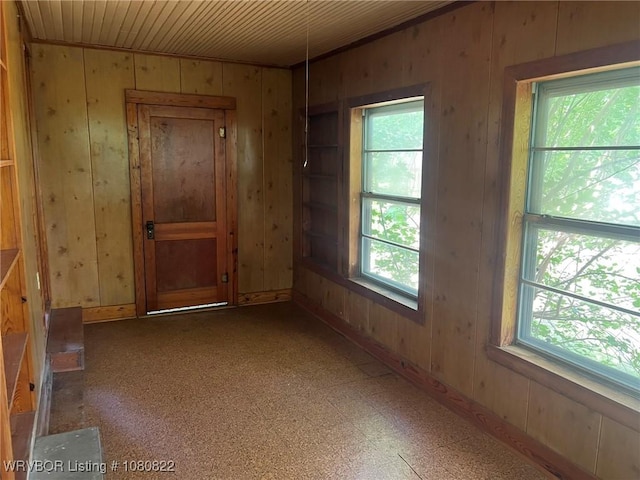 empty room featuring a wealth of natural light, wood walls, and wooden ceiling