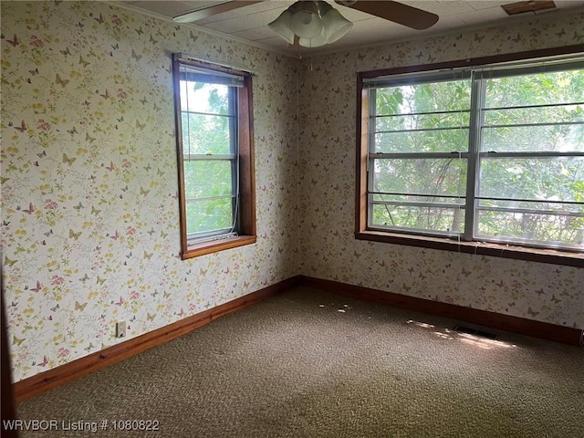 carpeted empty room with baseboards, a ceiling fan, and visible vents
