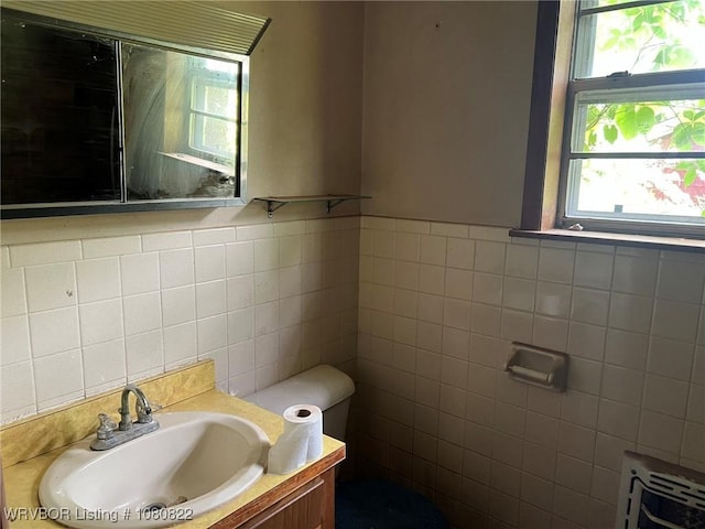 bathroom featuring toilet, tile walls, vanity, and heating unit