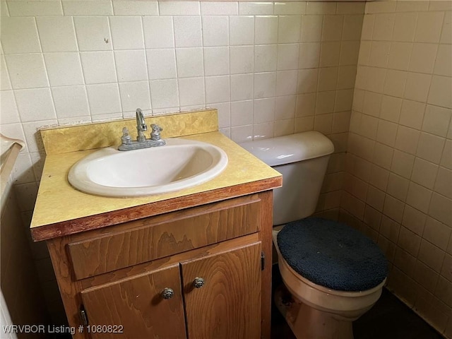 bathroom with toilet, tile walls, and vanity