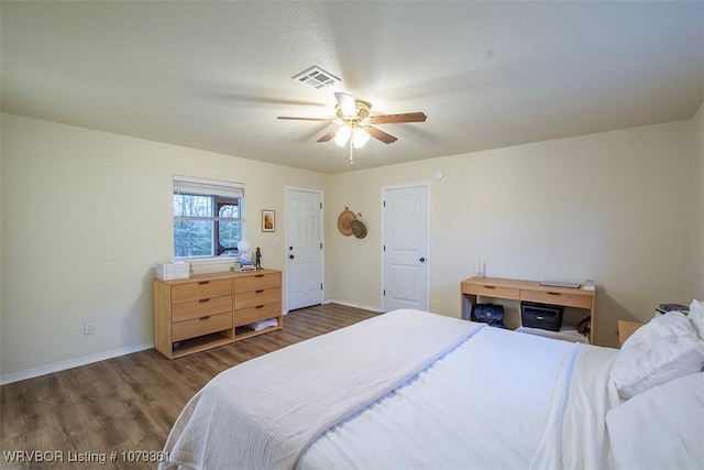 bedroom with a ceiling fan, wood finished floors, visible vents, and baseboards