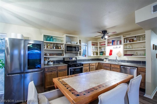 kitchen featuring a sink, stainless steel appliances, a textured ceiling, and open shelves