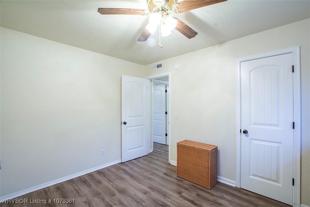 unfurnished bedroom featuring ceiling fan, wood finished floors, visible vents, and baseboards