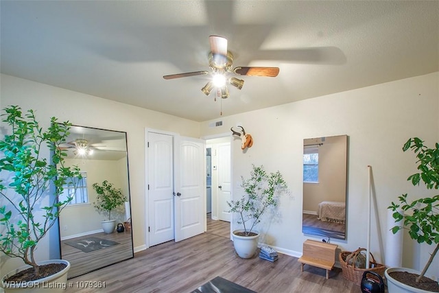 living area featuring ceiling fan, baseboards, and wood finished floors