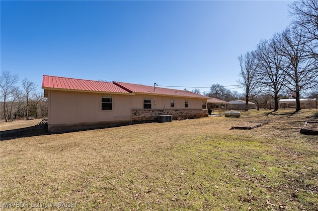 back of house featuring metal roof, central AC, and a yard