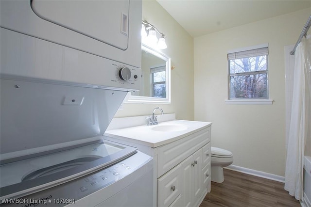 full bath with a healthy amount of sunlight, toilet, vanity, and stacked washing maching and dryer