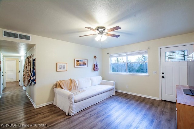 living area featuring baseboards, a textured ceiling, visible vents, and dark wood-style flooring