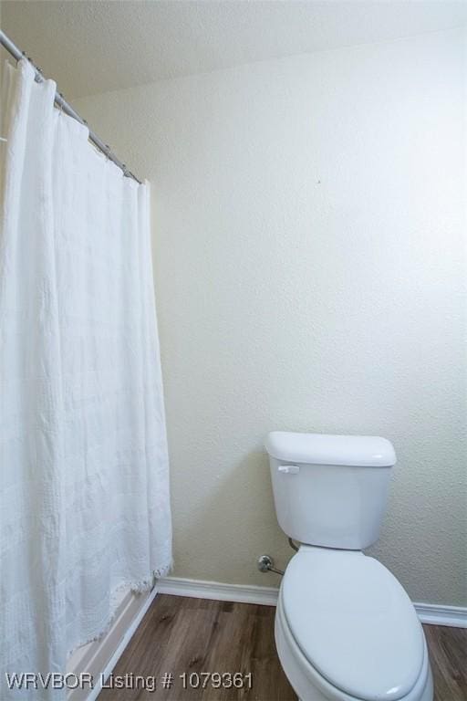 full bathroom with toilet, baseboards, and wood finished floors