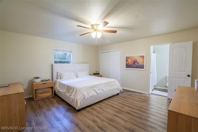 bedroom with a textured ceiling, baseboards, and wood finished floors