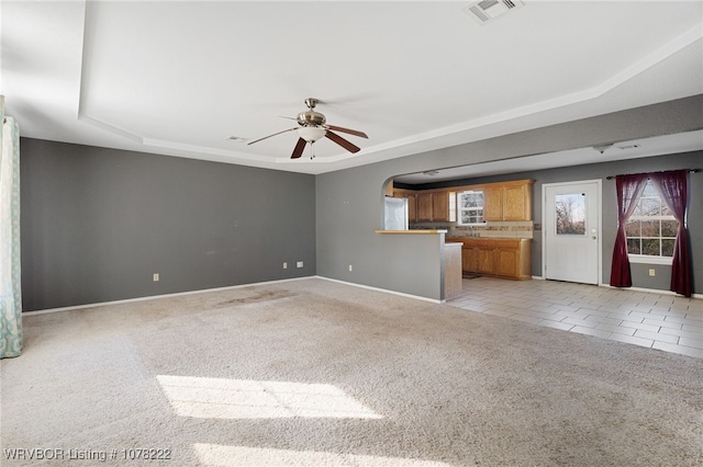 unfurnished living room featuring light tile patterned floors, a raised ceiling, and ceiling fan