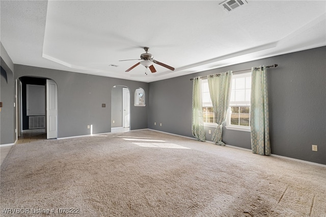 carpeted empty room with ceiling fan and a tray ceiling