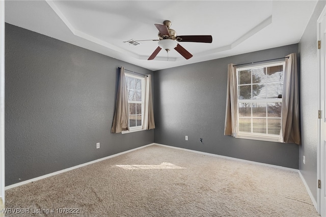 spare room featuring plenty of natural light, ceiling fan, carpet floors, and a tray ceiling