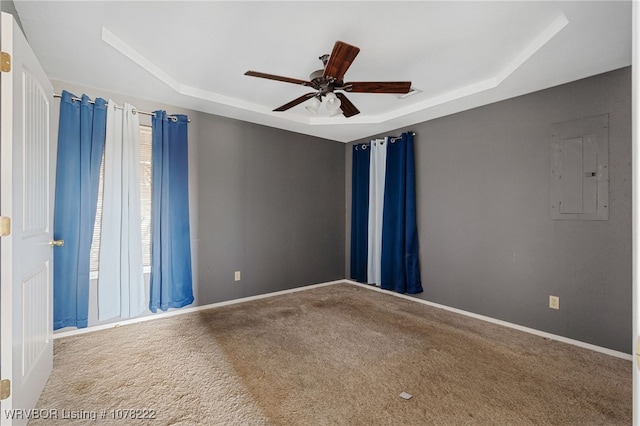 spare room featuring a raised ceiling, electric panel, ceiling fan, and carpet