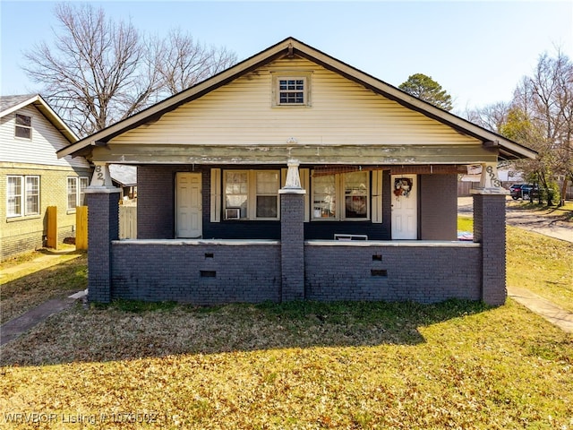 bungalow-style house featuring a porch, brick siding, and a front lawn