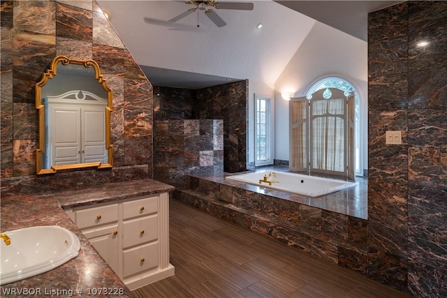 bathroom featuring vanity, tile walls, ceiling fan, and tiled tub