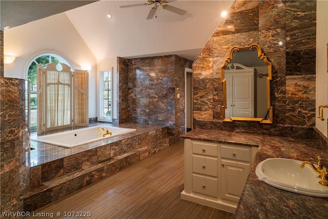 bathroom with vanity, ceiling fan, tile walls, tiled bath, and lofted ceiling