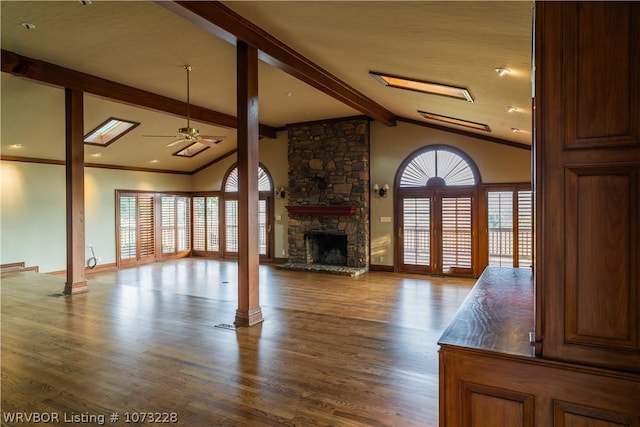 unfurnished living room featuring a wealth of natural light, a fireplace, ceiling fan, and lofted ceiling with beams