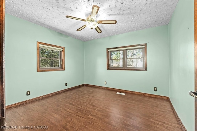 empty room featuring ceiling fan, a textured ceiling, baseboards, and wood finished floors