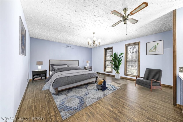 bedroom featuring visible vents, a textured ceiling, wood finished floors, an inviting chandelier, and baseboards