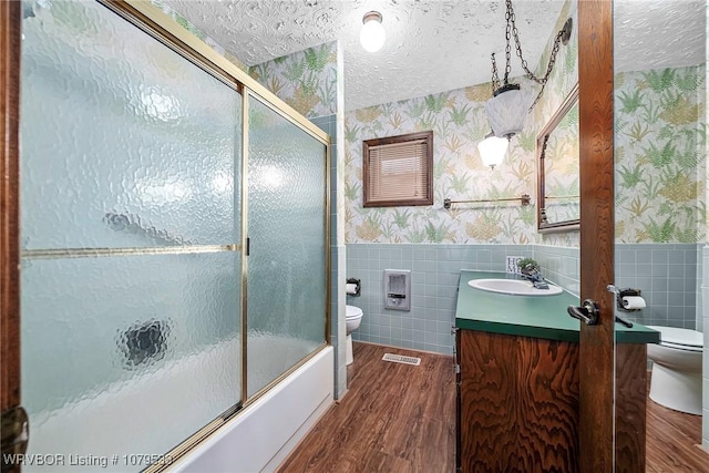 full bathroom featuring a wainscoted wall, toilet, and wallpapered walls