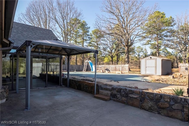 view of patio / terrace with an outbuilding, a fenced in pool, a fenced backyard, a gazebo, and a storage shed