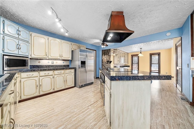 kitchen with island exhaust hood, a kitchen island, dark countertops, stainless steel appliances, and light wood finished floors