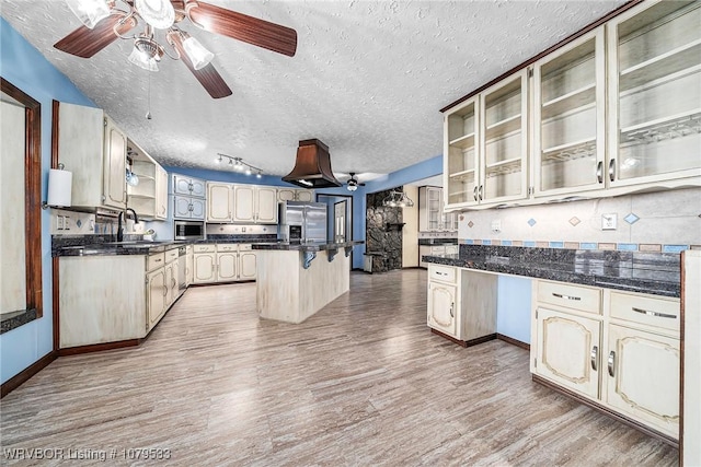 kitchen with a sink, a textured ceiling, light wood finished floors, and stainless steel appliances