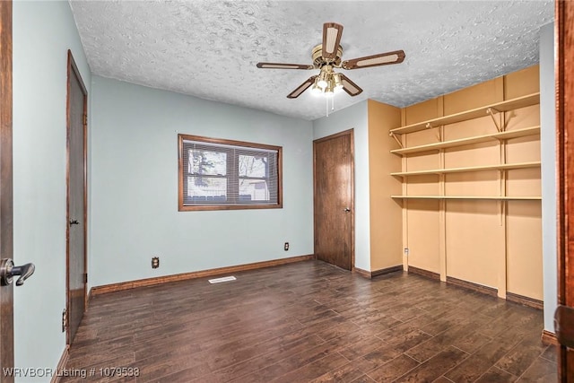 unfurnished bedroom featuring visible vents, a ceiling fan, a textured ceiling, wood finished floors, and baseboards