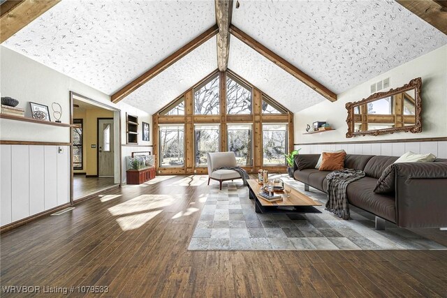 living area with visible vents, beam ceiling, high vaulted ceiling, wood-type flooring, and wainscoting