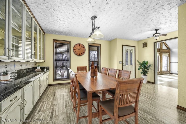 dining space featuring wood finished floors, baseboards, and a textured ceiling