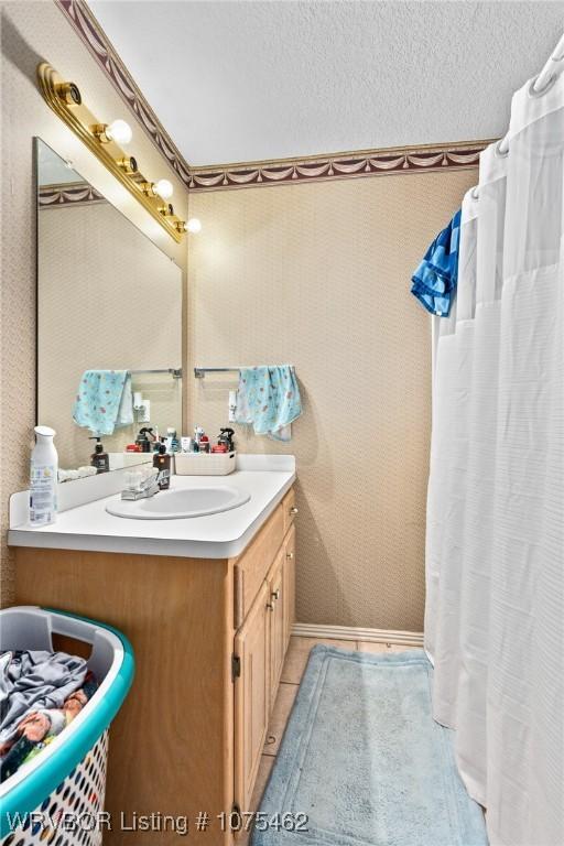 bathroom with tile patterned flooring, a textured ceiling, and vanity