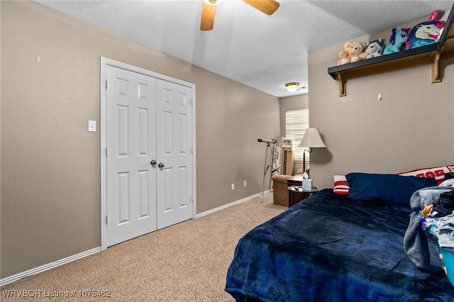 carpeted bedroom with ceiling fan, a closet, and a textured ceiling