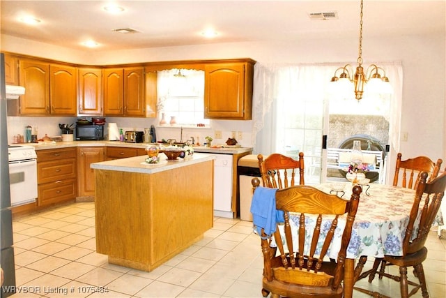 kitchen with stove, white dishwasher, hanging light fixtures, a kitchen island, and a chandelier